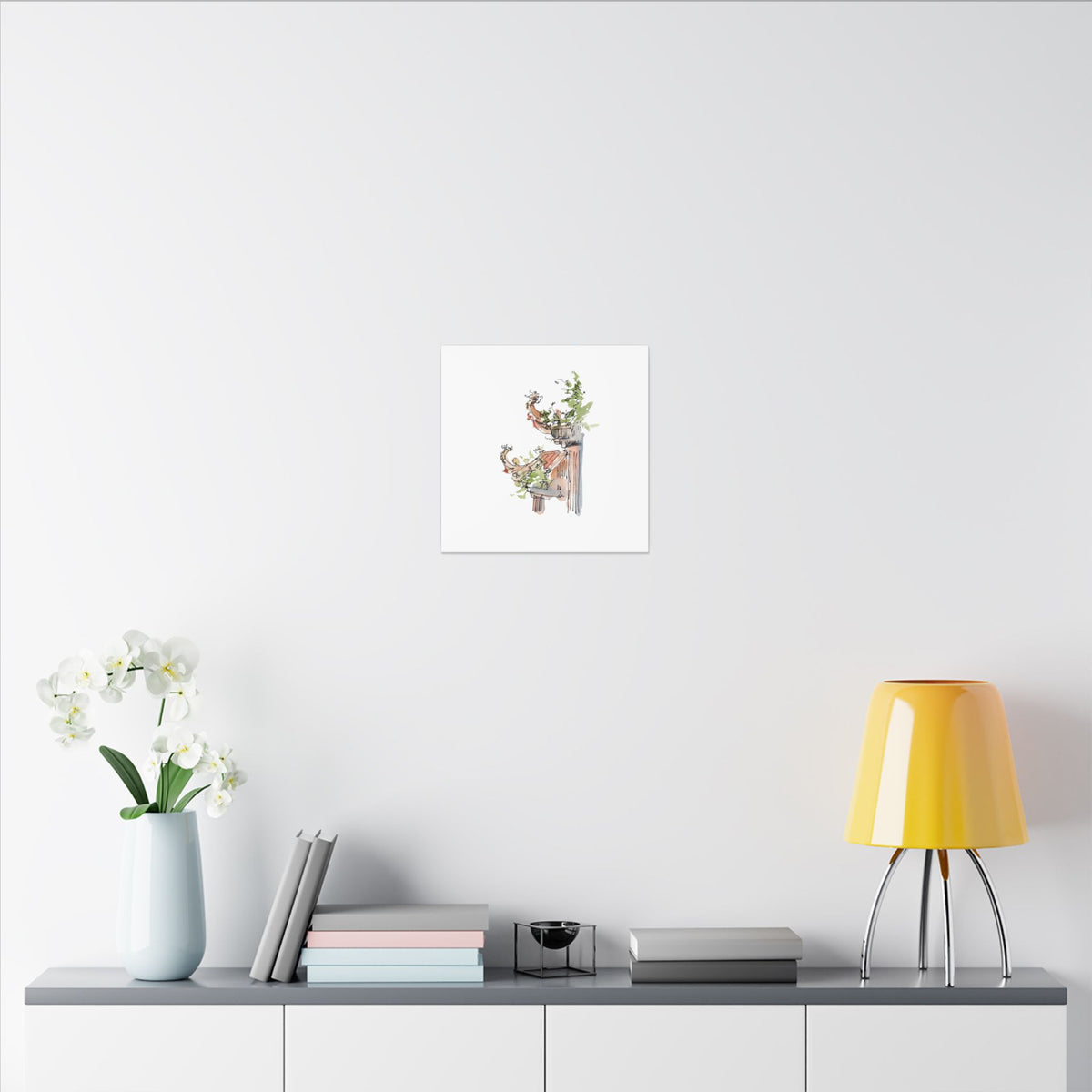 Decorative setup with a lamp, books, and a vase on a shelf against a white wall with a framed picture.